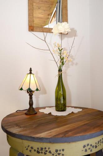 a table with a lamp and a vase with flowers on it at Kenderhordó Pihenőház in Zánka