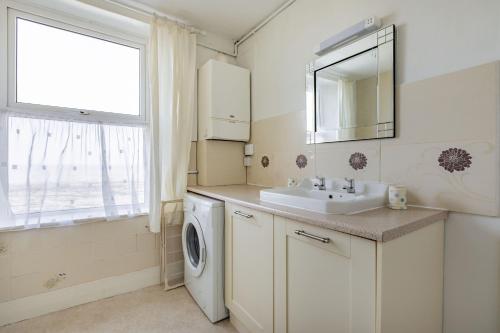 a white bathroom with a sink and a washing machine at Sea Spray in Watchet