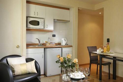 a kitchen with a table, chairs, and a refrigerator at Hotel Eurotel El Bosque in Santiago