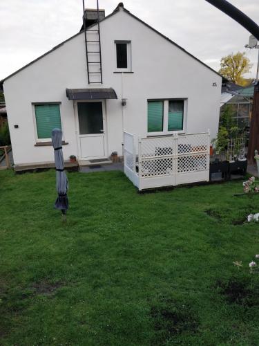 une maison blanche avec une pelouse devant elle dans l'établissement Gästehaus am Teich, à Raben Steinfeld