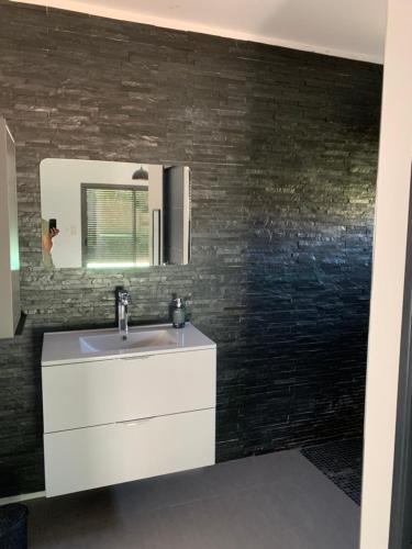 une salle de bain avec un lavabo blanc et un miroir dans l'établissement Villa Cosy avec piscine, à Pierrelatte