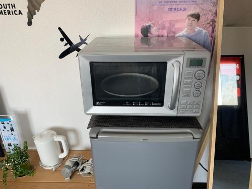 a microwave sitting on top of a refrigerator at 4人で一緒に熊本の中心地の最も広く安価な部屋 KDY stay in Kumamoto
