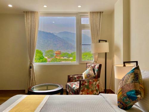 Green View by Green Tree Hotels في ريشيكيش: غرفة نوم بسرير ونافذة وكرسي