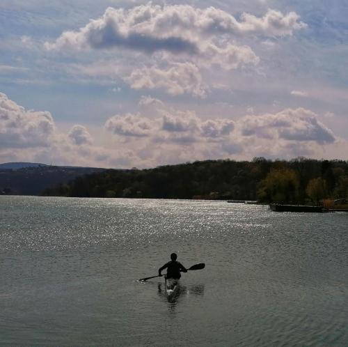 a man in a paddle boat on a lake at KalandFészek in Orfű