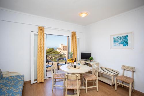 a living room with a table and chairs and a window at Apartamentos Piza in Colonia Sant Jordi