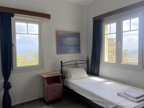 a bedroom with two beds and two windows at Andros Vineyard house with sea view in Sinétion