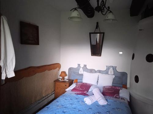 a bedroom with a blue bed with red and white pillows at Fecskefészek Vendégház Őriszentpéter in Őriszentpéter
