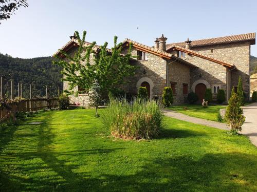 an old stone house with a green yard at Condado de San Martín in Boltaña