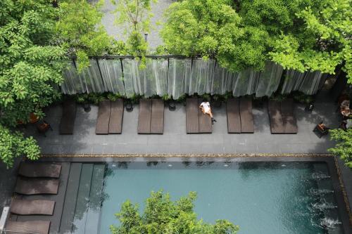 an overhead view of a person sitting on a bench next to a pool at BED Nimman - Adults Only in Chiang Mai