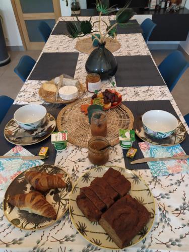 une table garnie de assiettes de pain et de viennoiseries dans l'établissement B&B Bel Agave, à Saint-Georges-des-Agoûts