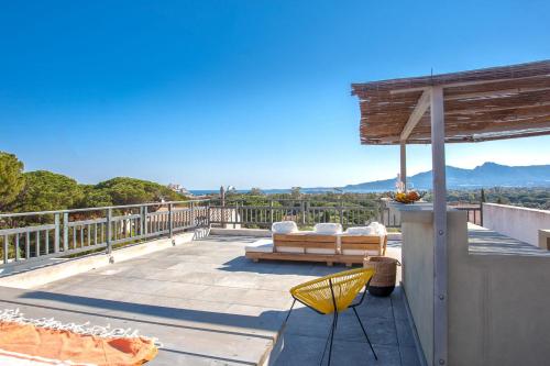 een patio met een tafel en stoelen op een balkon bij Villa avec piscine chauffée et vue mer proche centre et plage de Calvi in Calvi