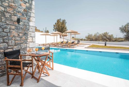 a villa with a swimming pool with chairs and a table at Terra Pietra Luxury Villas & Suites in Lardos