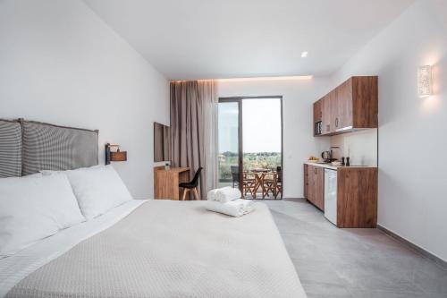 a bedroom with a large white bed and a kitchen at Terra Pietra Luxury Villas & Suites in Lardos