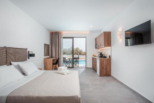 a bedroom with a bed and a kitchen with a pool at Terra Pietra Luxury Villas & Suites in Lardos