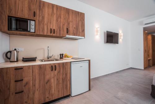a kitchen with wooden cabinets and a sink at Terra Pietra Luxury Villas & Suites in Lardos