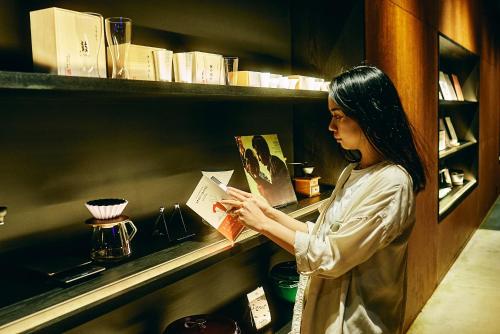 a woman is looking at a book on a shelf at 41 PIECES Sapporo in Sapporo