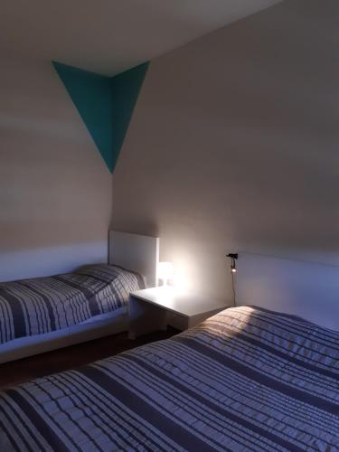 a bedroom with two beds and a light on the wall at 6daNoi bis in Ivrea