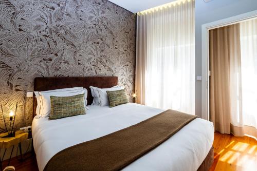 um quarto com uma grande cama branca e uma parede em Mouzinho 129 - Carvalho no Porto