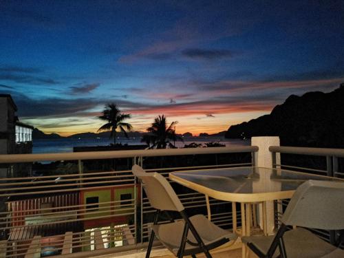 a balcony with a table and chairs and a sunset at Bayview Country Inn El Nido in El Nido