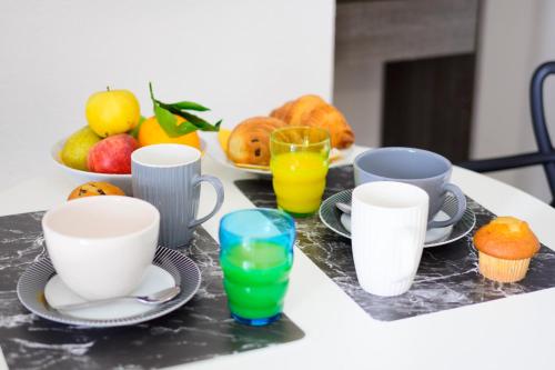 a table with cups and plates of food and fruit at Le 31-GregIMMO-Appart'Hôtel in Montbéliard