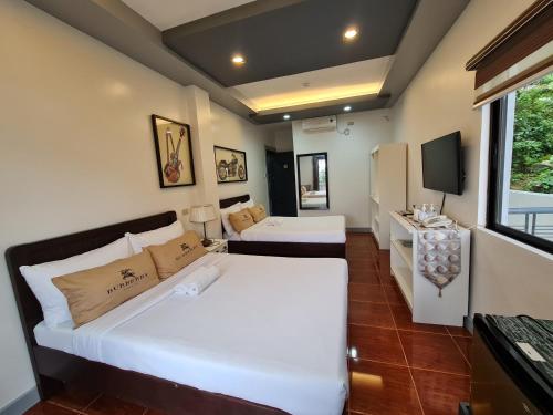 a hotel room with two beds and a television at Bayview Country Inn El Nido in El Nido