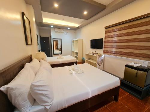 a hotel room with two beds and a television at Bayview Country Inn El Nido in El Nido