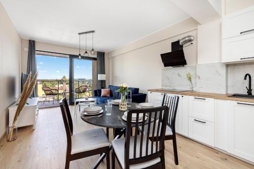 a kitchen and dining room with a table and chairs at Apartament 409 Natural Darłówko in Darłowo