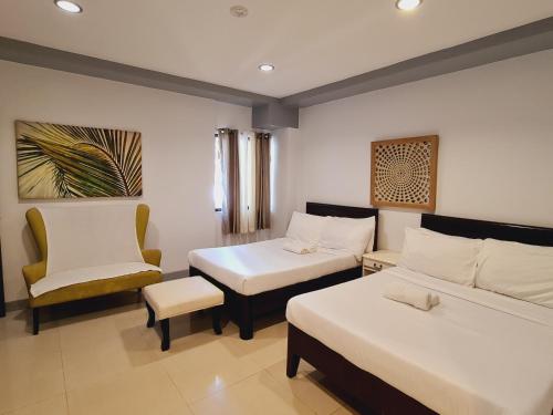 a room with two beds and a chair at Bayview Country Inn El Nido in El Nido