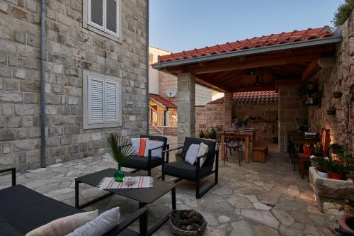 a patio with chairs and a table and a stone wall at Apartments Micika in Cavtat