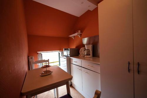 a small kitchen with orange walls and a wooden table and chair at Pension am Dom in Schwerin