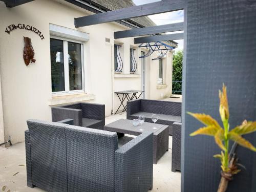 un patio avec des tables et des chaises dans un bâtiment dans l'établissement Ker Gaouenn - moderne & cosy (pergola, jardin, terrasse géante...) - bonne connexion - intime (guide personnalisé en cadeau), à Les Fougerêts