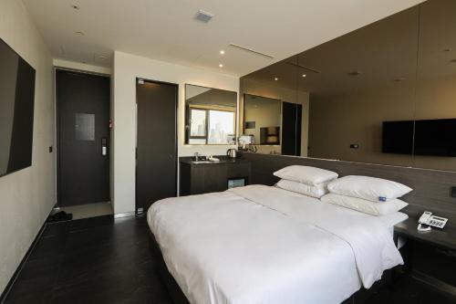 a bedroom with a large white bed and a bathroom at Hotel The Designers Hongdae in Seoul