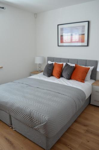 a bed with orange and grey pillows in a bedroom at Exclusive Ensuite Double Room in London