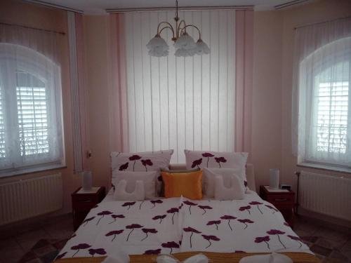 a bedroom with a white bed with flowers on it at Manor Villa in Hévíz