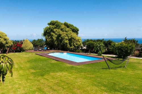 a swimming pool in a field of grass with the ocean in the background at Traditional Arucas by VillaGranCanaria in Arucas
