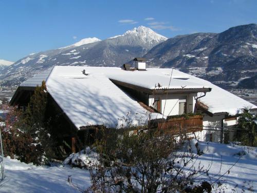 a house covered in snow with a mountain in the background at Unterbrunnerhof in Lana