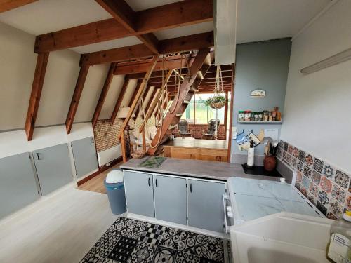 une cuisine avec des placards blancs et un escalier en arrière-plan dans l'établissement Chalet de vacances au bord de mer VER SUR MER, à Ver-sur-Mer