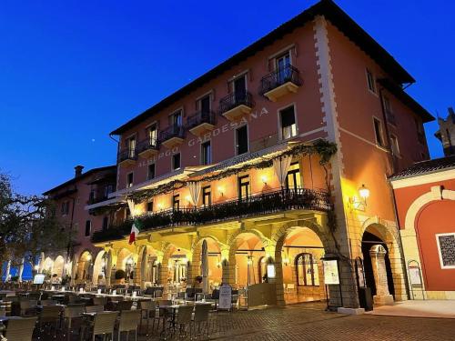 a large building with tables and chairs in front of it at Albergo Gardesana in Torri del Benaco