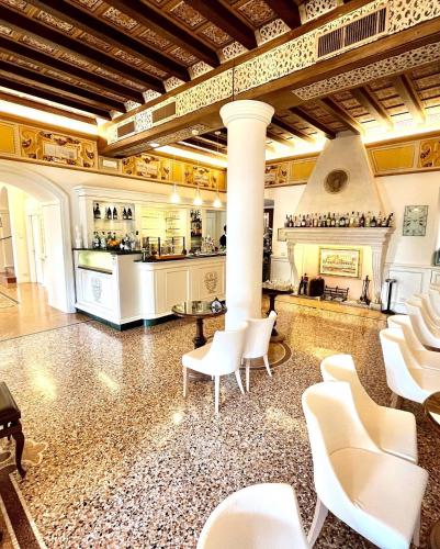 a room with white chairs and a kitchen in a building at Albergo Gardesana in Torri del Benaco