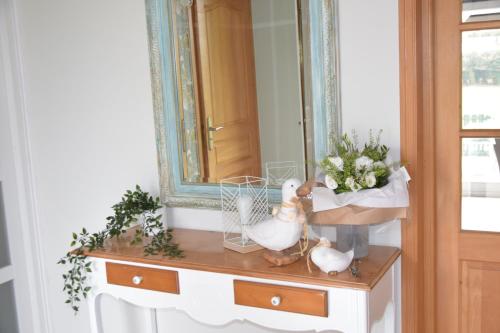 a dressing table with a mirror and flowers on it at Les chambres du Vert Galant "La campagne qui murmure" in Verlinghem