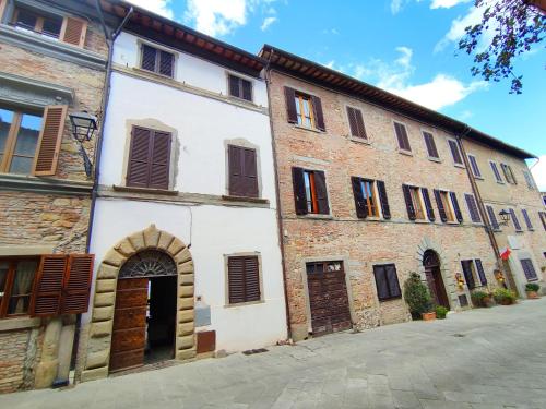 a white building with brown shutters on a street at Casa degli Artisti in Citerna