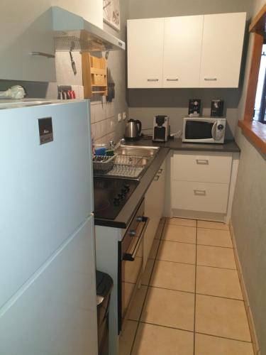 eine kleine Küche mit weißen Schränken und einem Kühlschrank in der Unterkunft LE RELAX in Lurcy-Lévis