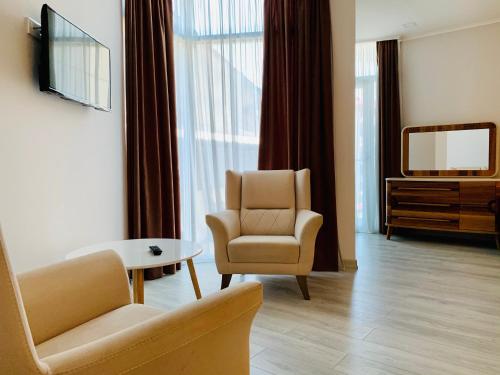 バトゥミにあるHotel Tsereteli Palaceのリビングルーム(ソファ、テレビ、椅子付)