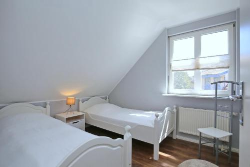 Cette petite chambre comprend 2 lits et une fenêtre. dans l'établissement Papillon Wohnung 04-5, à Boltenhagen