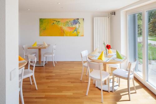 a dining room with white tables and chairs and a painting at Le Domaine (Swiss Lodge) in Fribourg