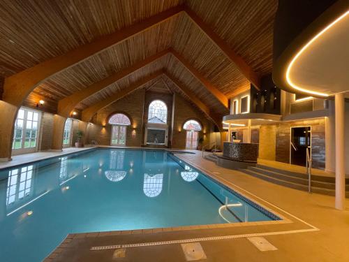 a large swimming pool in a building with a wooden ceiling at Park Farm Hotel in Norwich