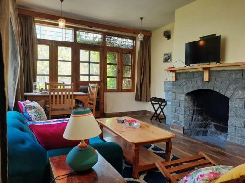 a living room with a couch and a fireplace at Cliffer Cottage: Make Mountains Memorable! in Manāli