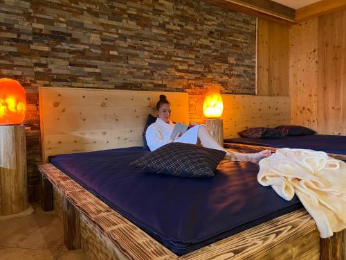 a woman laying on a bed reading a book at Vitalhotel Gosau in Gosau
