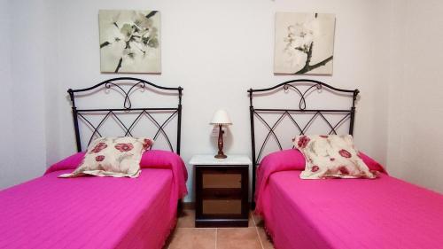 two beds in a room with pink sheets at Center of the Sea, Three rooms - Alojamientos La Torre in Torre del Mar