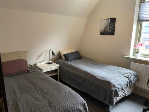 a bedroom with two beds and a table with a lamp at Lejlighed med egen indgang midt i Nykøbing Falster in Nykøbing Falster